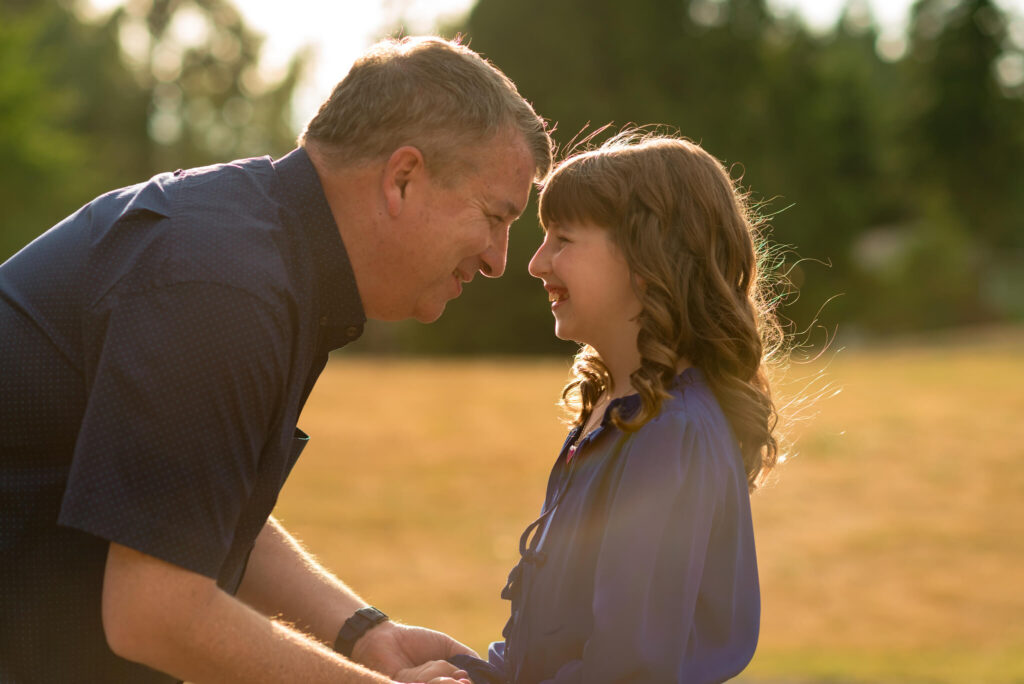 Dad and daughter smiling forehead-to-forehead during a golden hour family photo session in Castle Rock, Colorado.