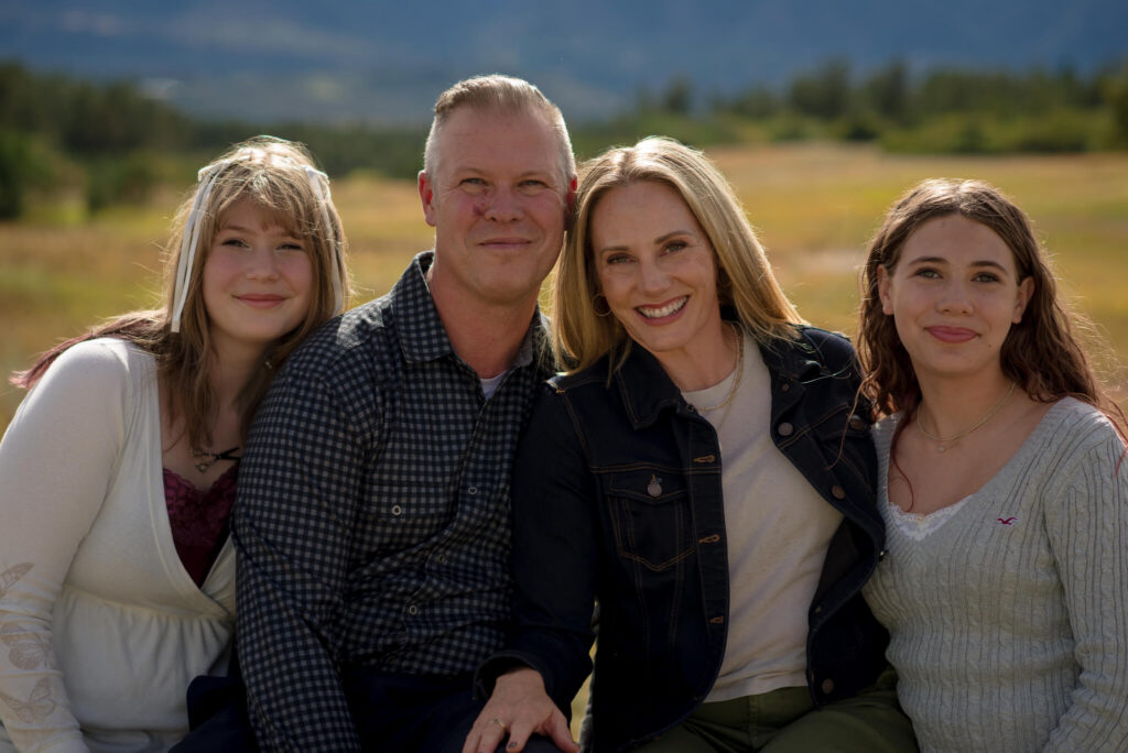 Family of four posing together in a golden Colorado meadow during a Castle Rock summer family photography session.
