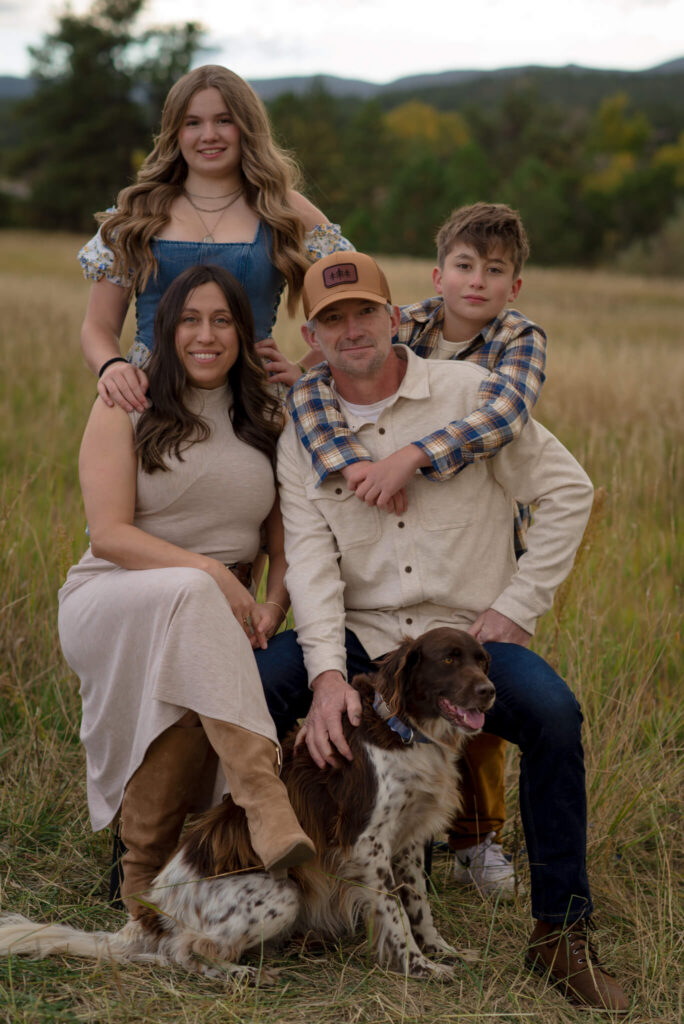 Family portrait with their dog in an open field during golden hour near Castle Rock, Colorado.