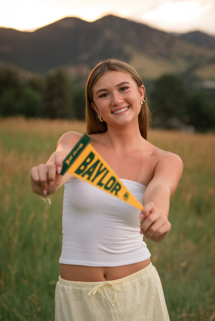 Castle View High School senior proudly holding a Baylor University pennant at Chautauqua Park in Boulder during golden hour.