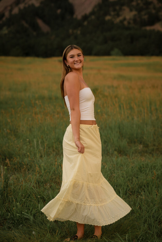 Castle View High School senior smiling during a sunset photo session at Chautauqua Park with the Boulder foothills behind her.