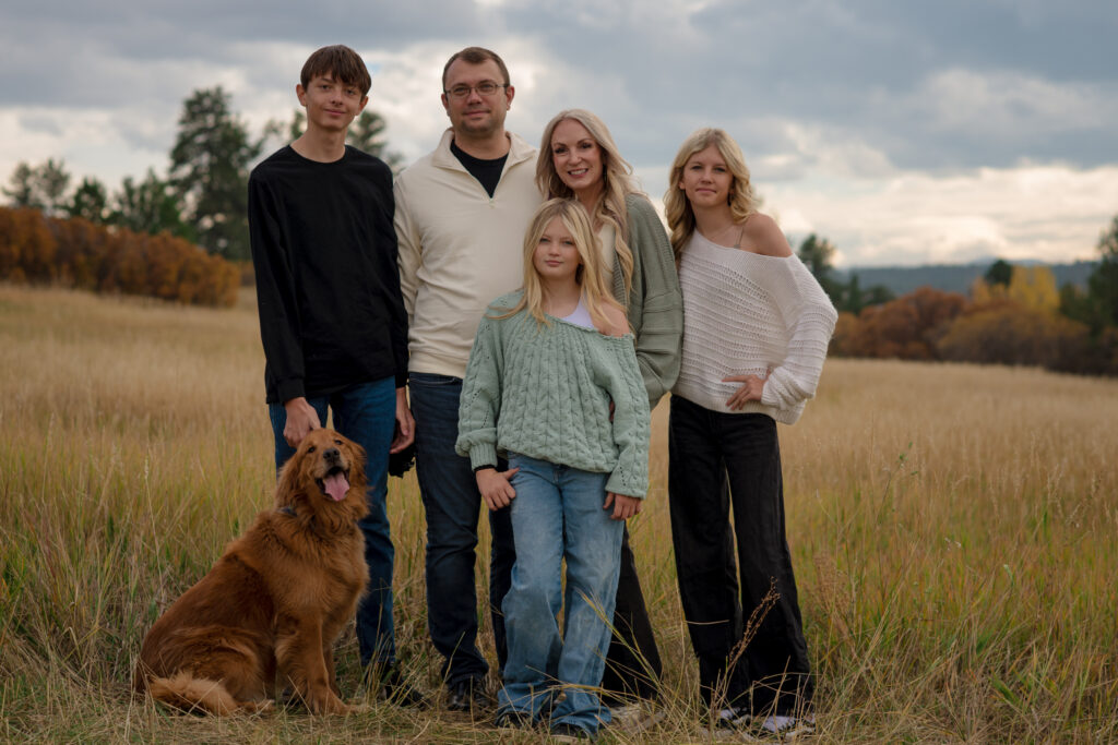 Family of five with their golden retriever posing together in a golden field during a fall family mini session in Castle Rock, Colorado.