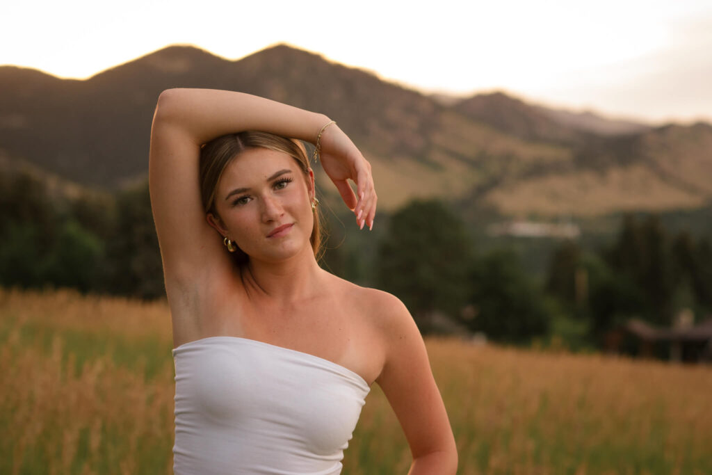 High school senior posing outdoors in a Colorado field with mountain views during a Castle Rock Senior Photography session.