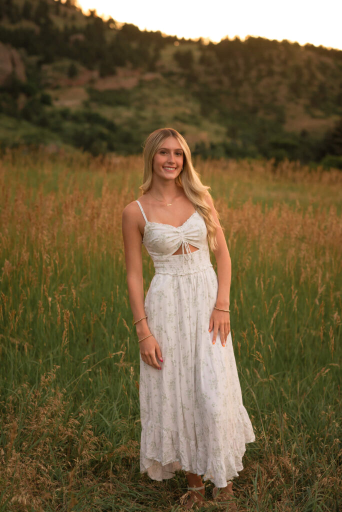 High school senior standing in a grassy field at Boulder Chautauqua State Park during an outdoor senior photo session at golden hour.